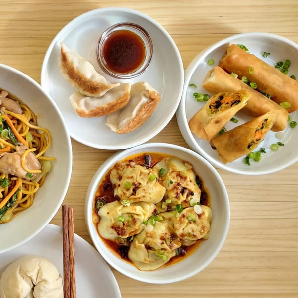 Assortment of Brooklyn Dim Sum Co. dishes: noodles, dumplings, spring rolls, and a steamed bun.