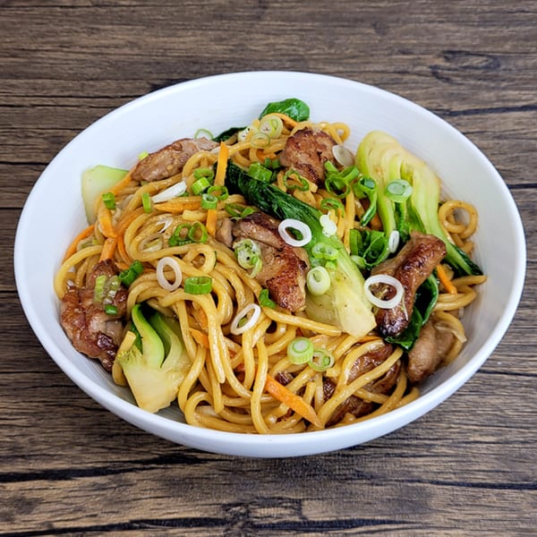 Brooklyn Dim Sum Co's lo mein with chicken, bok choy, carrots, and scallions in a white bowl.