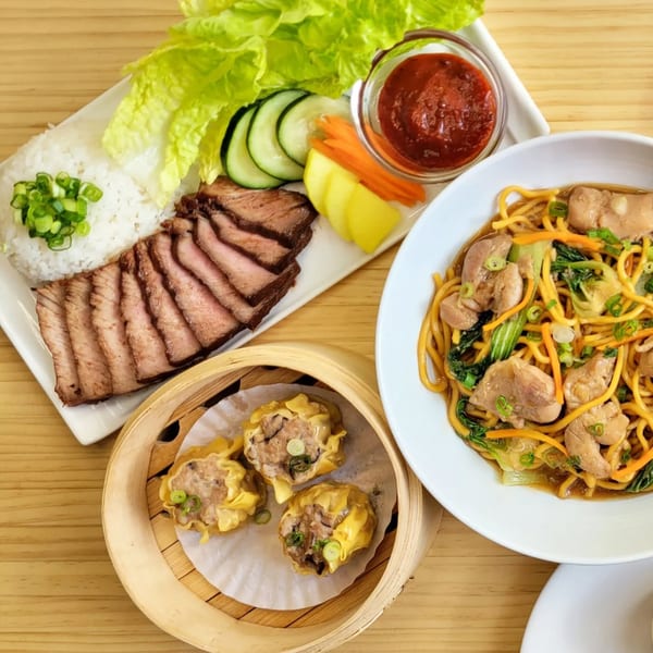 A spread of Brooklyn Dim Sum Co dishes: sliced meat, rice, vegetables, noodles, and shumai.
